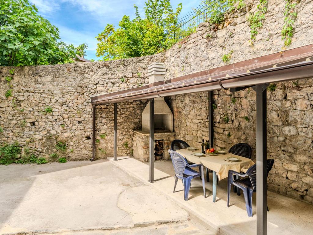 a patio with a table and chairs and a stone wall at Apartment Sabo by Interhome in Porlezza