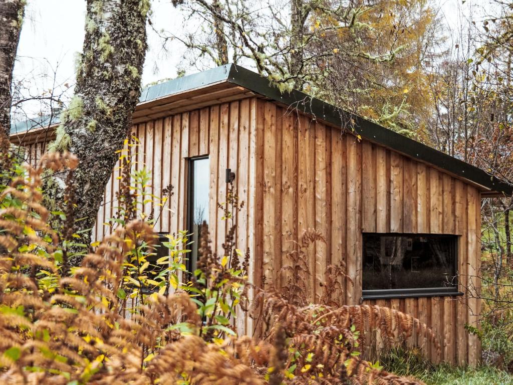 a wooden cabin in the woods with a window at Holiday Home G-Wilderness Cabin by Interhome in Errogie