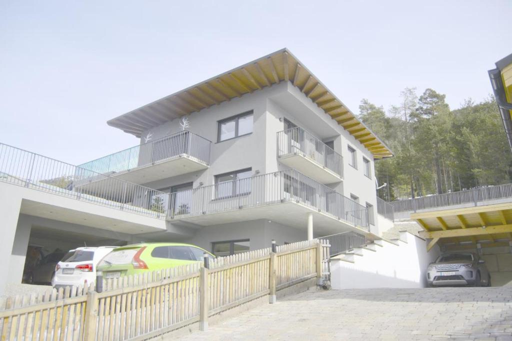 een wit huis met auto's ervoor geparkeerd bij Appartement ALPINOVA by MoniCare in Reith bei Seefeld