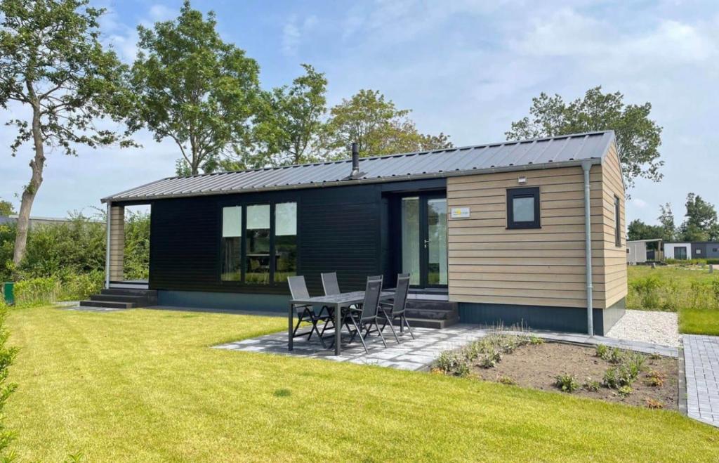 a small cabin with a table and chairs in a yard at Vakantiepark de Zeeuwse Parel - de Parel in Sint Maartensdijk