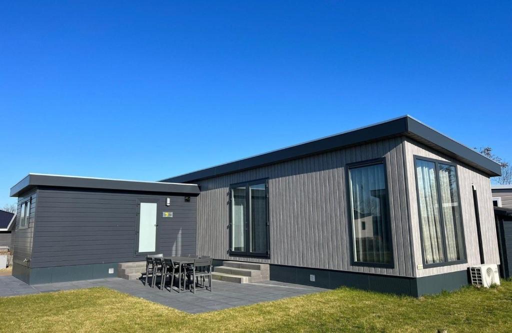 a modular home with chairs and tables in a yard at Vakantiepark de Zeeuwse Parel - De Zeester in Sint Maartensdijk