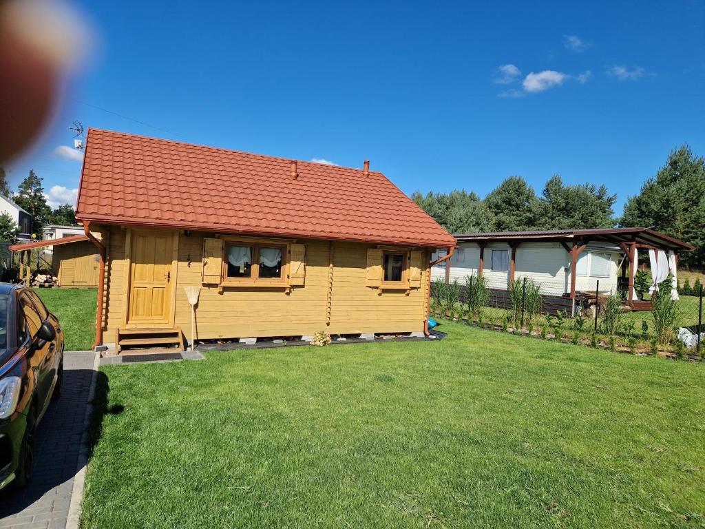 a small house with a red roof on a yard at Magiczny domek in Drzewoszewo