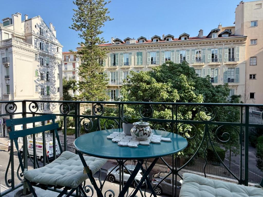 a table and chairs on a balcony with a building at Appartement niçois au coeur du triangle d'or in Nice