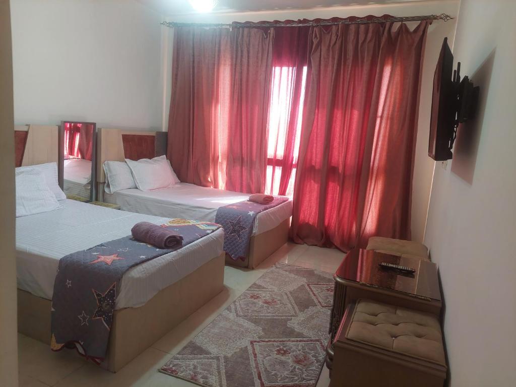 a bedroom with two beds and a window with red curtains at بورتو كايرو التجمع الخامس in Cairo