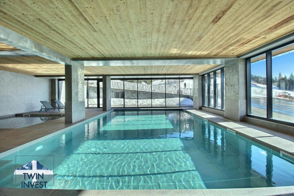 a swimming pool in a building with a wooden ceiling at ARC 1600, LE RIDGE, Appartement 06 personnes Vue Montagne - ski aux pieds - Sauna, Hammam, Piscine in Arc 1600