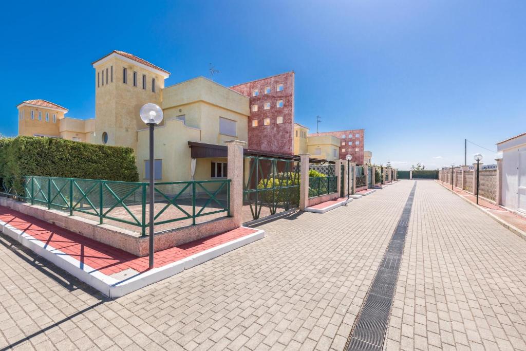 a brick street with a fence and some buildings at Residence Horizont in Margherita di Savoia