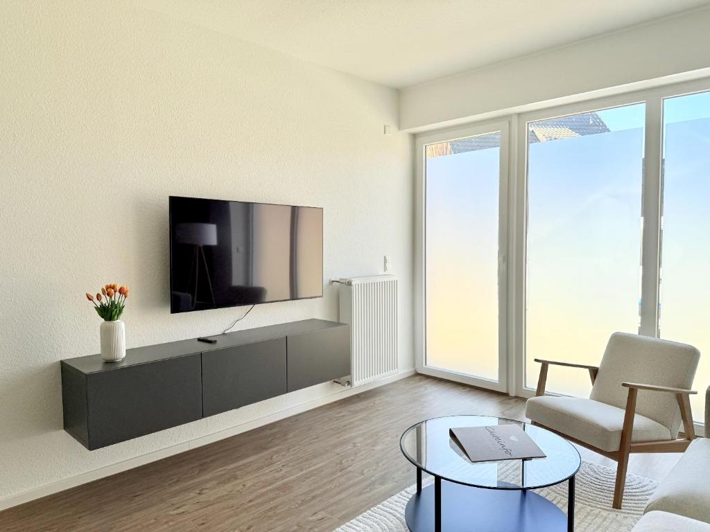 a living room with a tv and a chair and a table at Apartmenthaus Gilden 7 in Borken