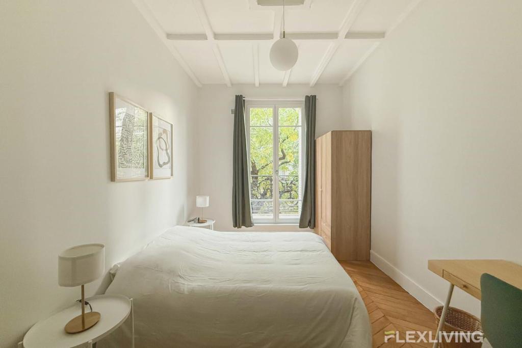 パリにあるCozy Room in Alésia Paris 14thのベッドと窓のある白い寝室