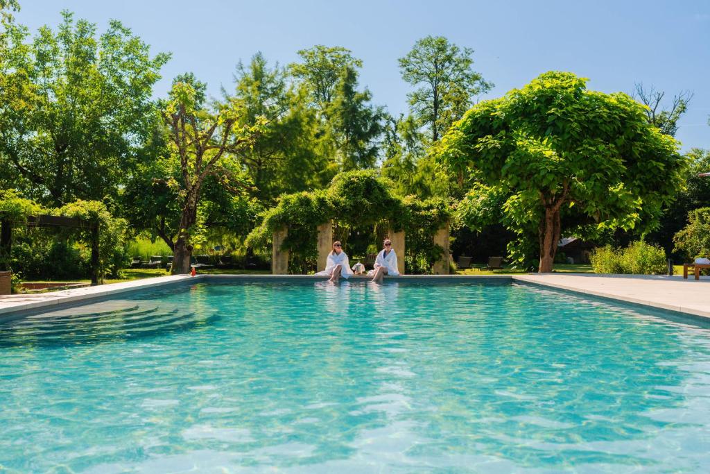 two people sitting on the edge of a swimming pool at Chateau De Germigney in Port-Lesney