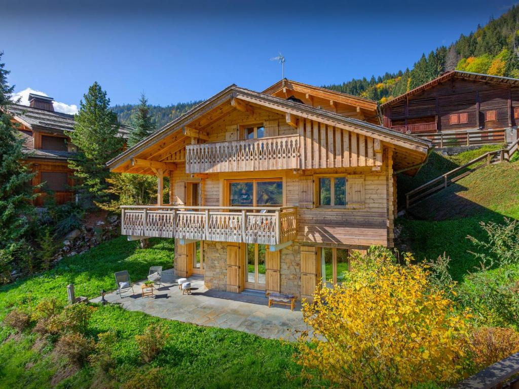 una gran casa de madera con terraza en una colina en Chalet Aravista - OVO Network, en Le Grand-Bornand