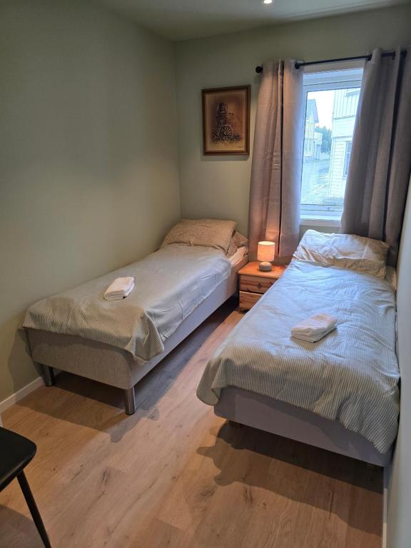 ein Schlafzimmer mit zwei Einzelbetten und einem Fenster in der Unterkunft Flott moderne leilighet meget sentralt i vakre Sørbyen i Brønnøysund for inntil 5 pers in Brønnøysund
