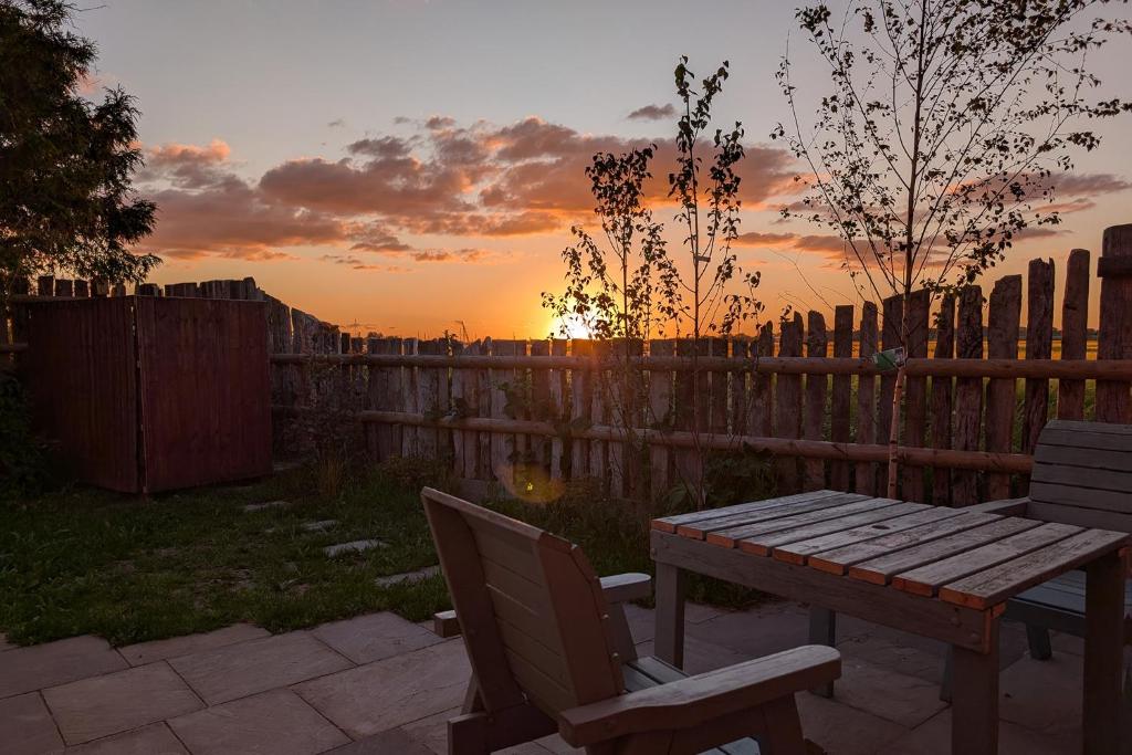 a wooden picnic table and chairs in a backyard at sunset at Grapnells Lodge, Wallasea Island, Rochford, Essex in Rochford