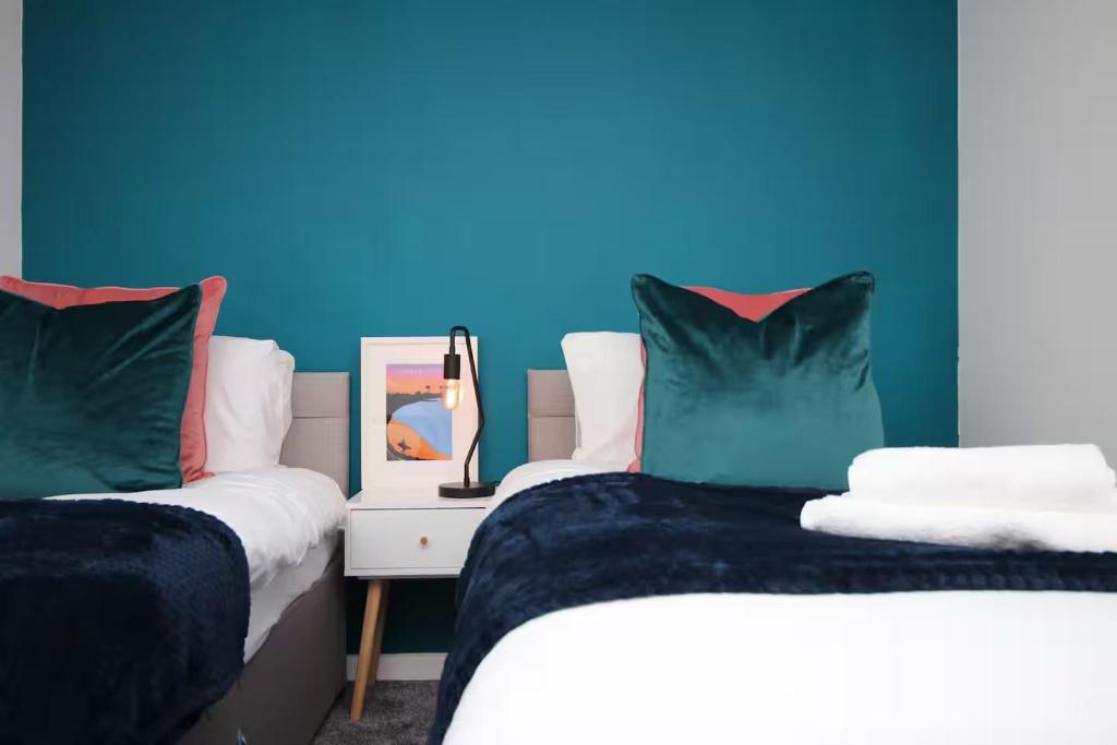 zwei Betten in einem Zimmer mit einer blauen Wand in der Unterkunft Home with Ocean View - Contractors and Families in Port Talbot