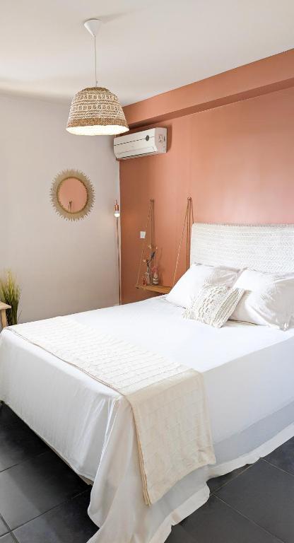 un letto bianco in una camera da letto con parete rosa di Perle d'Océan a Saint-Leu
