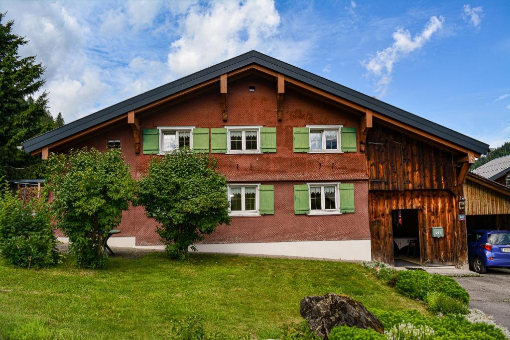 a brick house with green shutters on it at Villa Mondschein in Au im Bregenzerwald