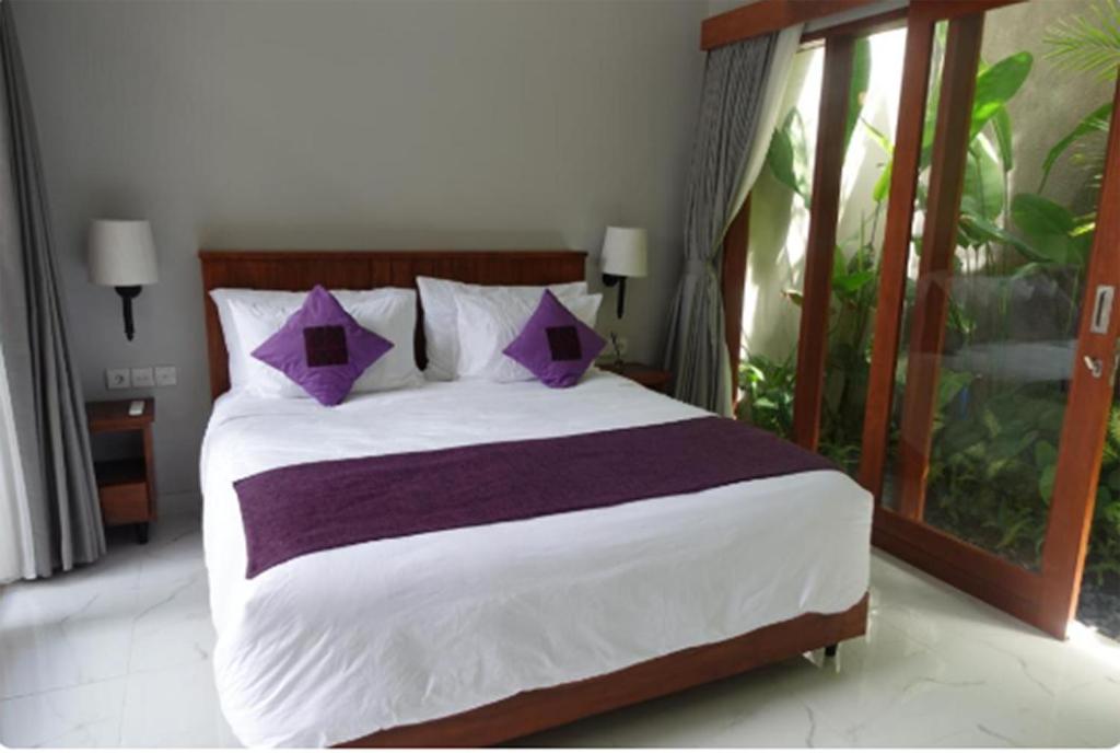 a bedroom with a large bed with purple pillows at Near to The Beach Ayunjani Villa, Bali in Ketewel