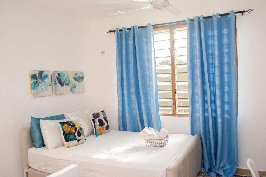 a room with blue curtains and a bed with a window at Marve in Mtwapa