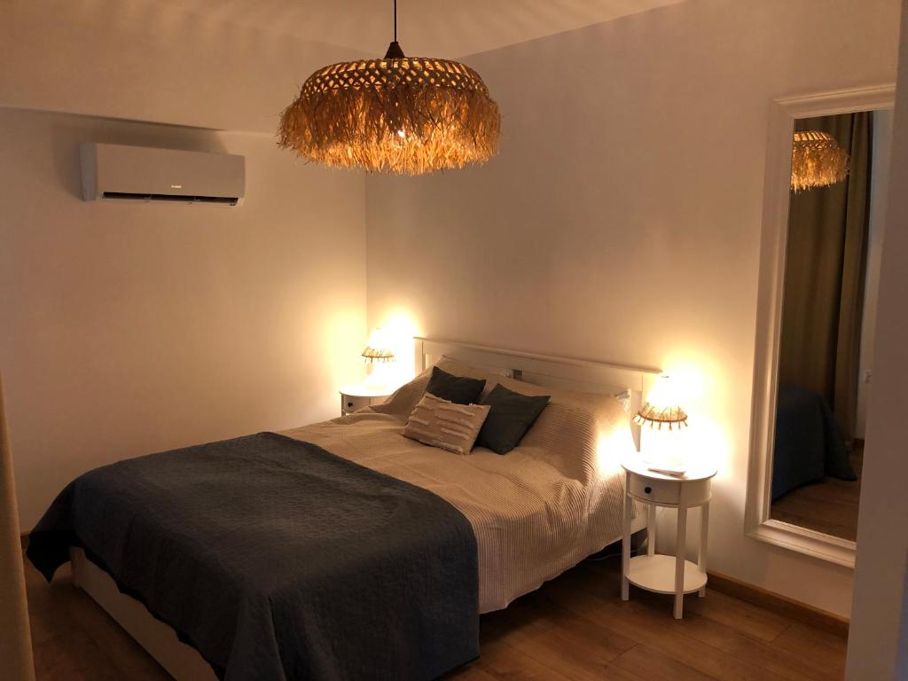 a bedroom with a bed with two tables and a chandelier at Гнездото l The Nest in Burgas City