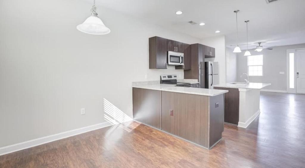 eine Küche mit Holzböden und eine Küche mit einer Theke in der Unterkunft Upscale King 3BR Townhouse Pineville in Charlotte