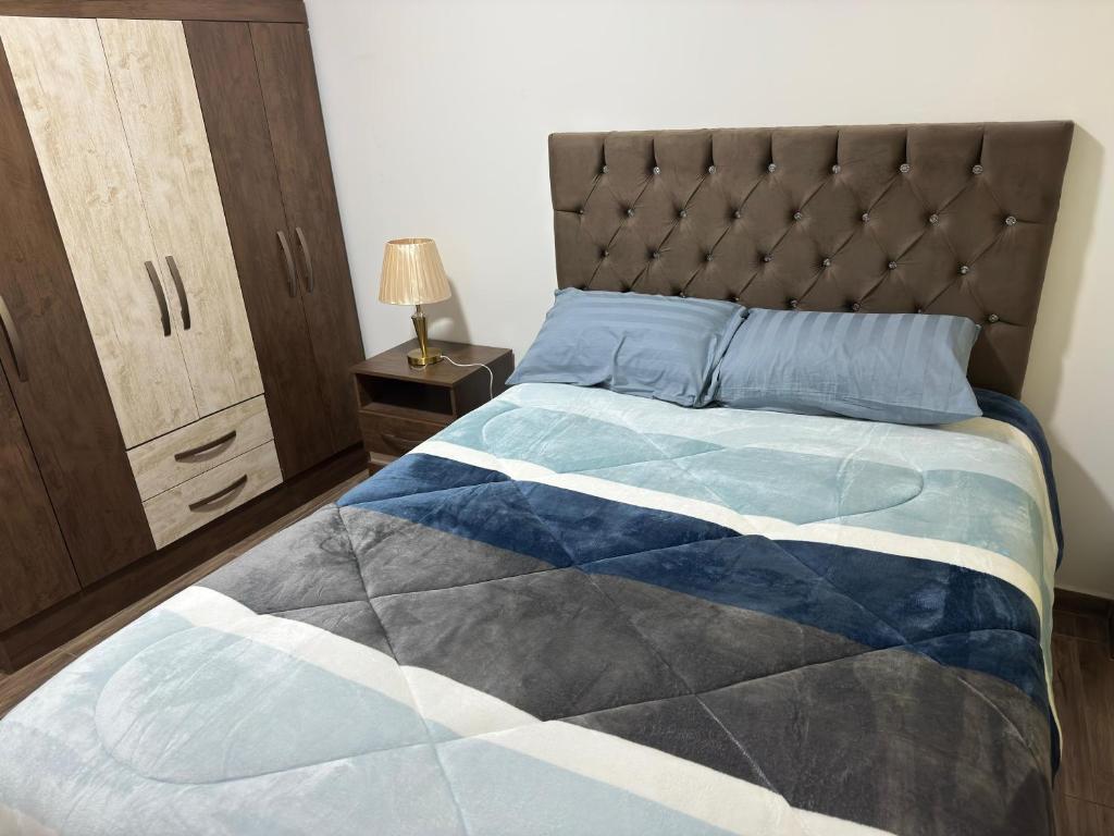 a bedroom with a bed with a blue and white quilt at Las Palmas Apart in Tacna