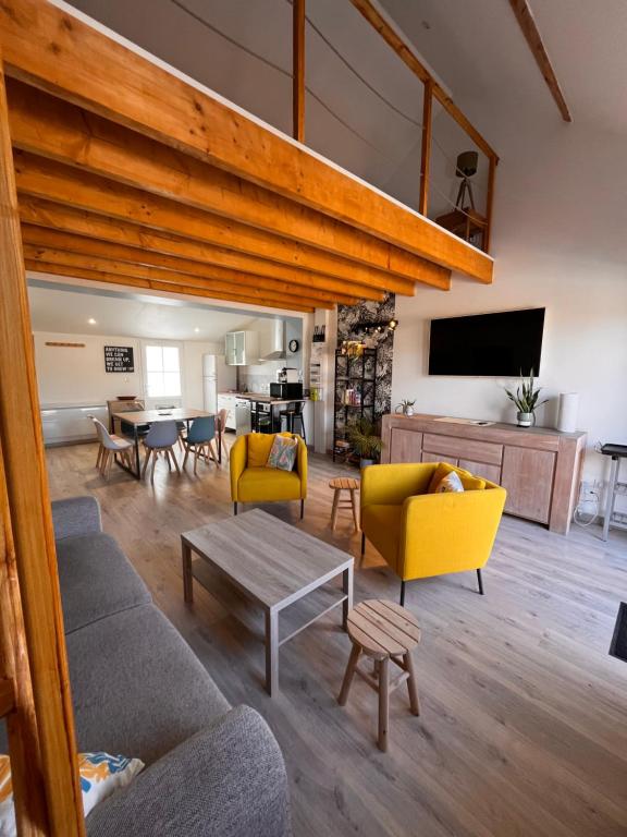 a living room with yellow chairs and a table at Aux Pas Sages, 4 logements mitoyens, proche mer in Saint-Jean-de-Monts