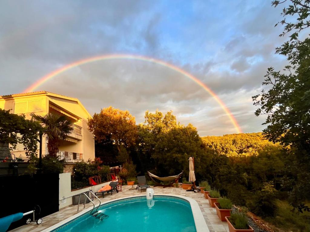 a rainbow in the sky over a swimming pool at Villa Theresa Kroatien in Donji Zagon