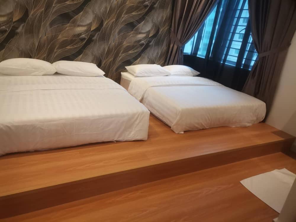 two beds sitting next to each other in a bedroom at Adik Aisyah black forest luxury cameron homestay in Tanah Rata