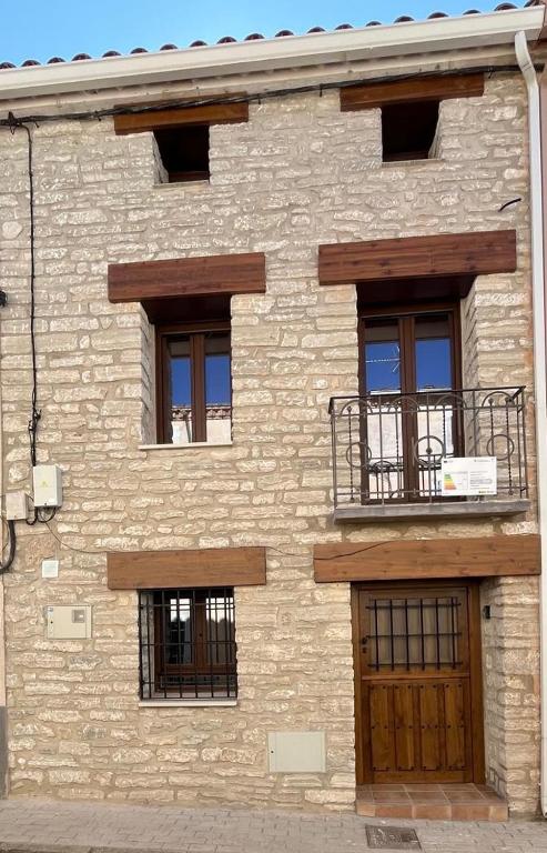 a brick building with a balcony and a wooden door at La casa de la tía Guille in Medranda