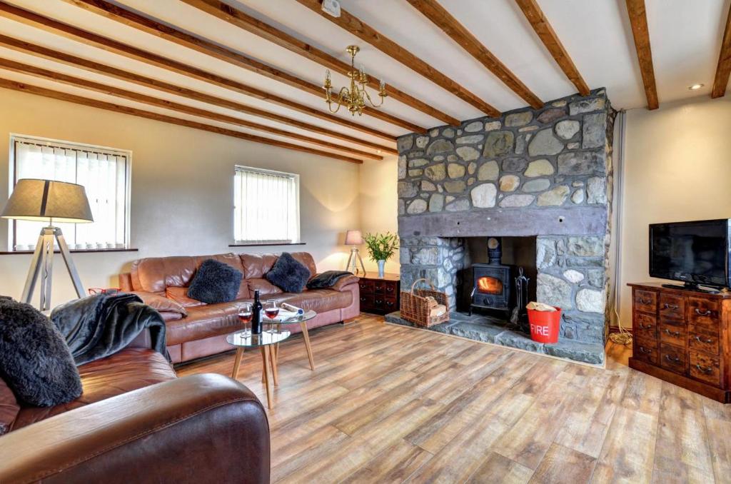 a living room with a couch and a stone fireplace at Yr Efail in Y Felinheli