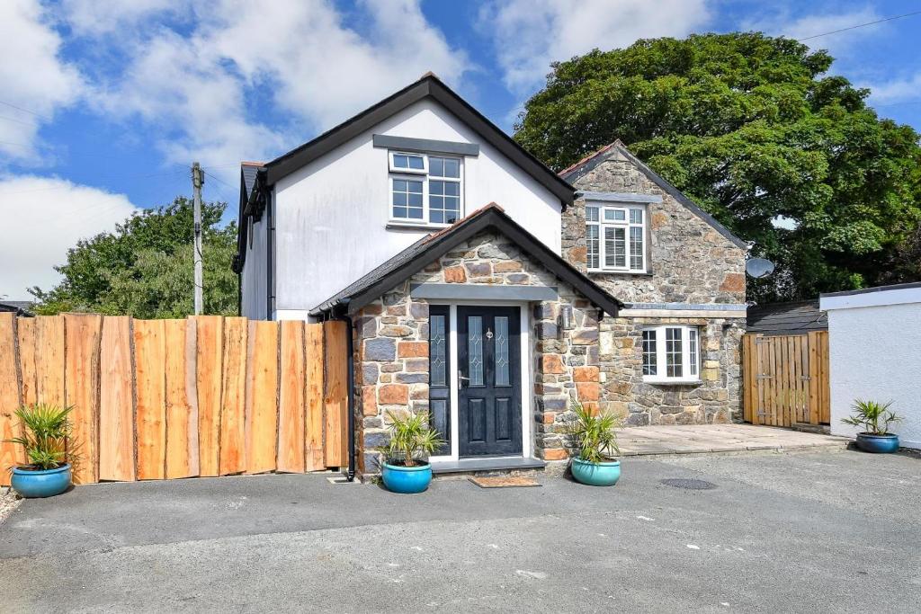 a stone house with a wooden fence and potted plants at Egryn Bach in Abersoch