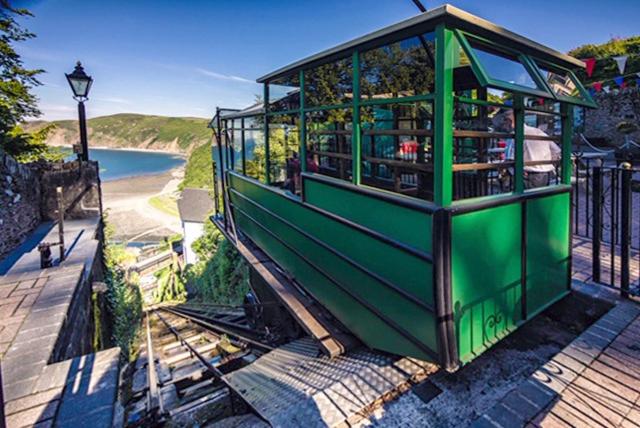 a small green building with a view of the beach at The Den in Lynmouth