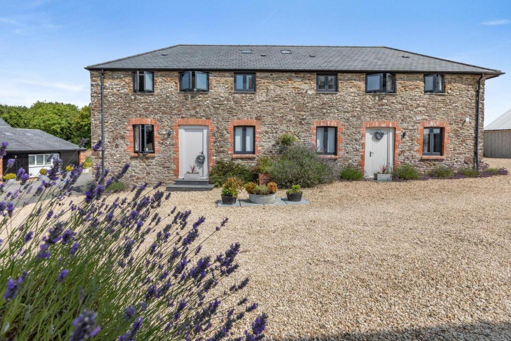 a stone house with flowers in front of it at Austen Cottage - Swanmoor Grange in Chapelton