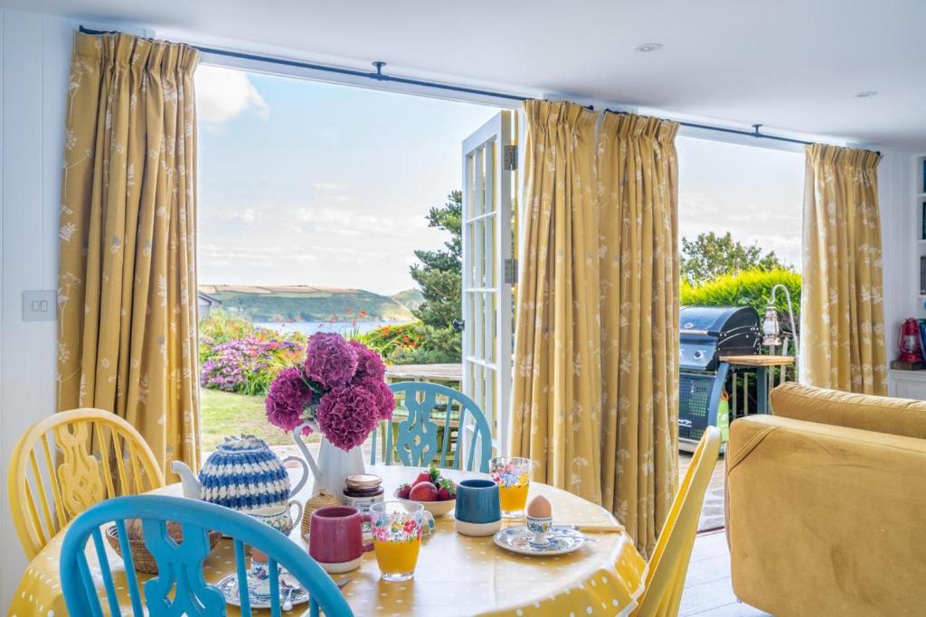 Una mesa y sillas en un balcón con vista al mar. en Bel-Nor-Cot, en Cawsand