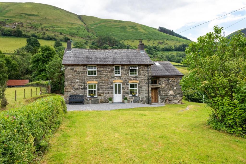 una vieja casa de piedra en medio de un campo en Y Felin, en Machynlleth