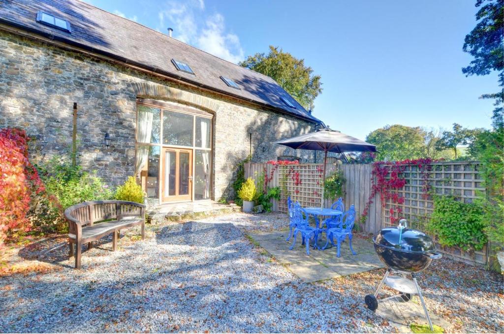 a stone house with a grill and a table and chairs at Threshing Barn in Llansawel