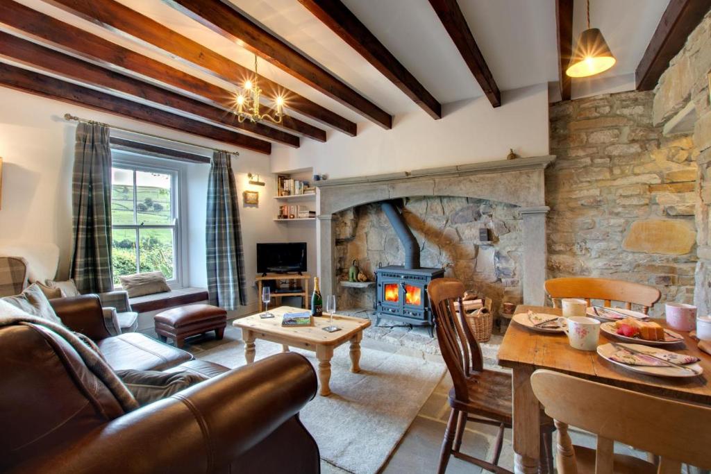 a living room with a fireplace and a stone wall at Wardell Hall Cottage in Feetham