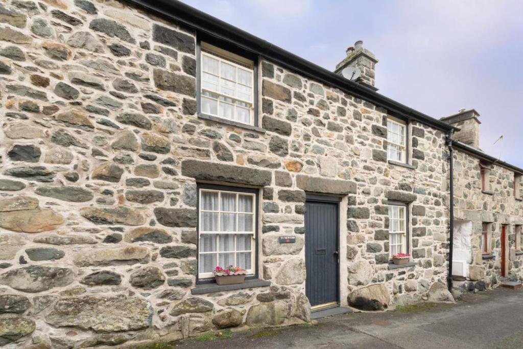 an old stone building with two windows and a door at Ty Newydd in Dolgellau
