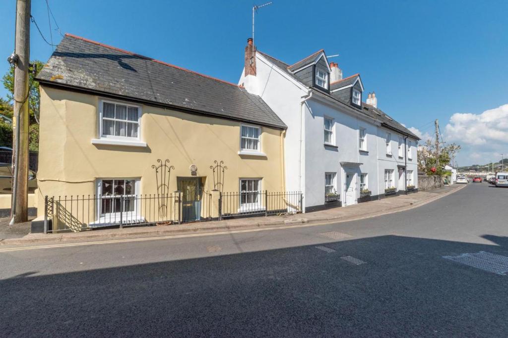 a yellow and white house on the side of a street at Drum Cottage in Appledore