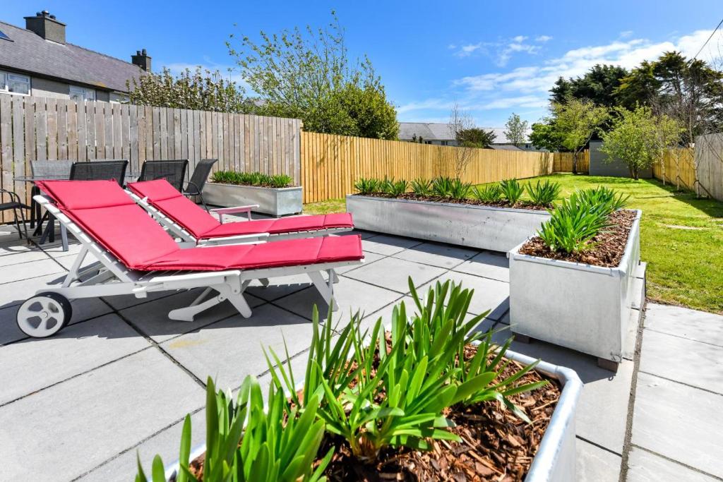 a patio with a red table and chairs in a backyard at 16 Maes Gwydryn in Abersoch