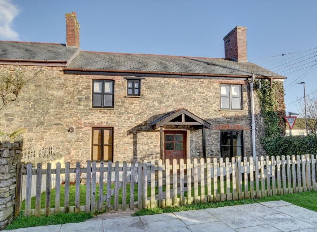 a brick house with a white picket fence at Cross Farm Cottage in Braunton