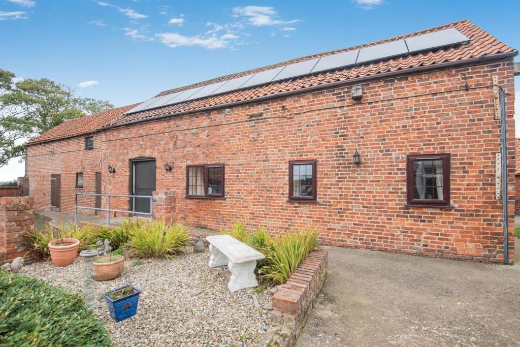 Lark Rise Cottage - 3 White Hoe Farm في Kirton in Lindsey: مبنى من الطوب وامامه مقعد