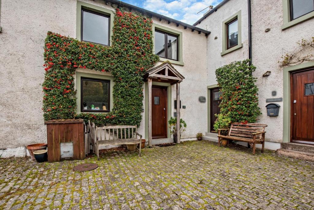 a house with two benches in front of it at Rosie Cottage in Bassenthwaite