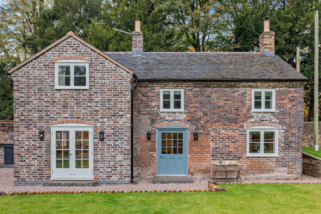 a brick house with a blue door and windows at Hall Cottage in Eccleshall