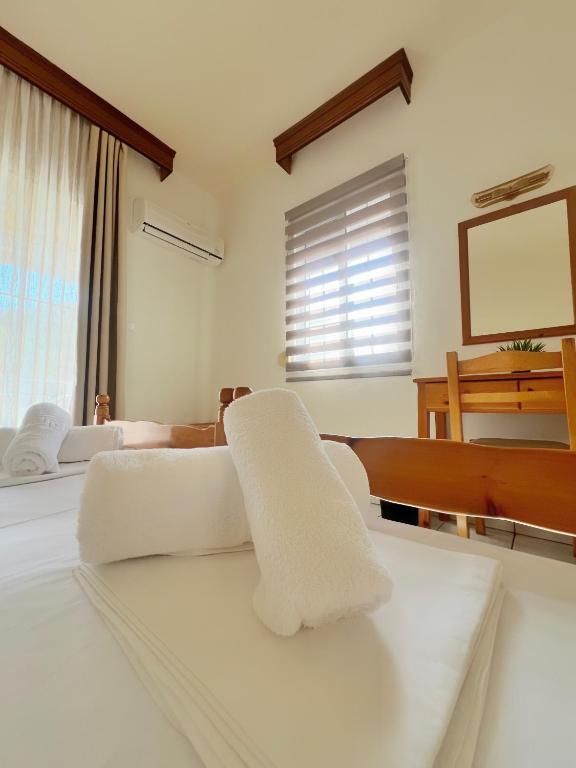 a white bedroom with white furniture and a piano at Maria's Rooms in Skala Rachoniou