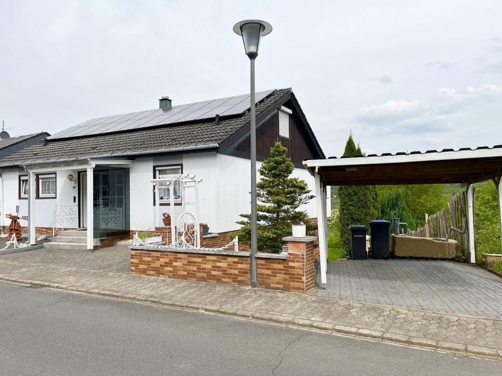 a white house with a porch and a brick wall at Malerisches Ferienhaus in Reil in Reil
