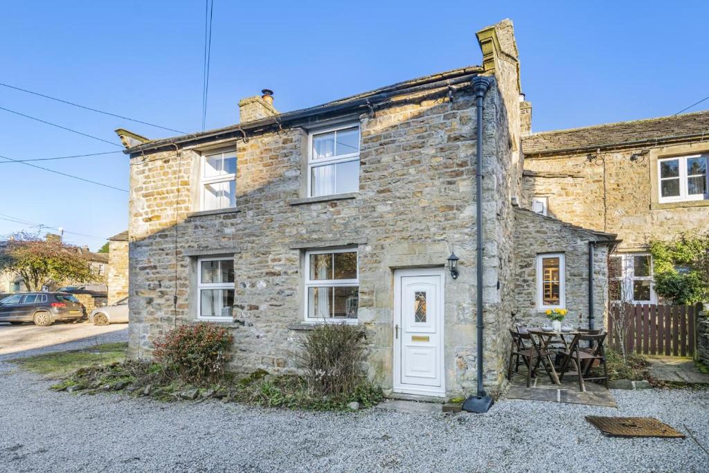 una vieja casa de piedra con una puerta blanca en Cherry Tree Cottage - Langthwaite, en Low Eskcleth