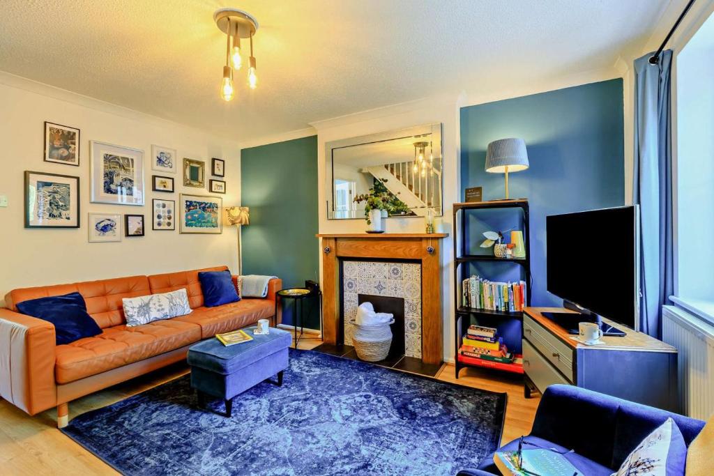 een woonkamer met een bank en een open haard bij Pink Cottage in Beer