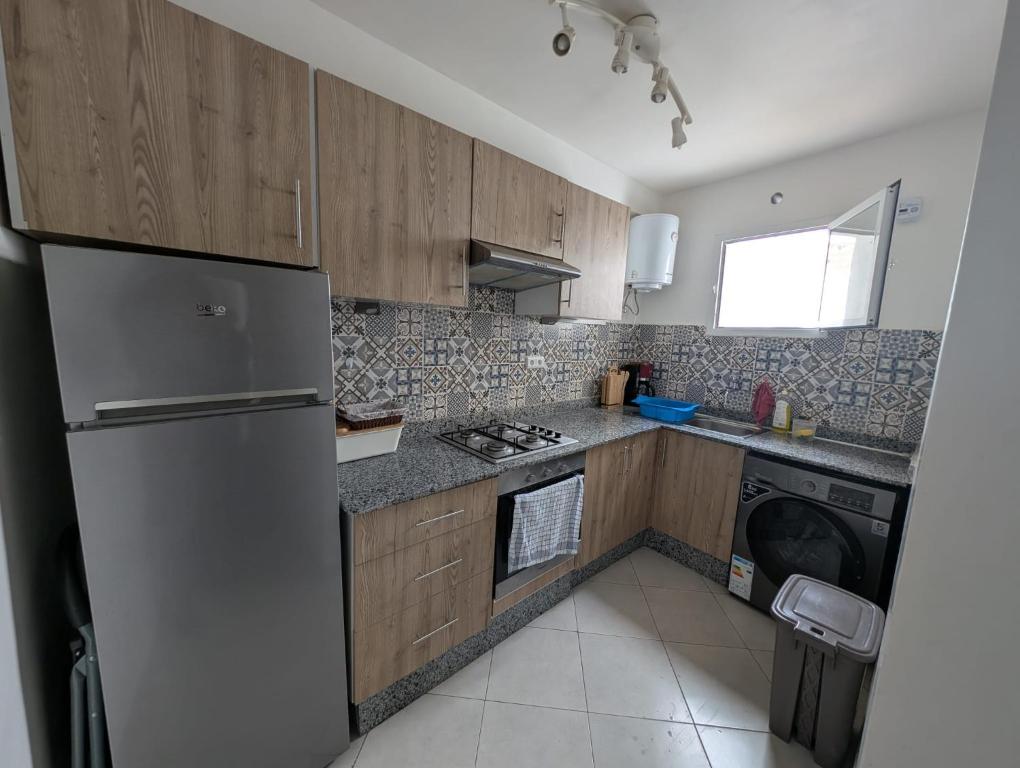 kuchnia z drewnianymi szafkami i lodówką w obiekcie Appartement Anza Agadir Meftah Sahel w mieście Agadir