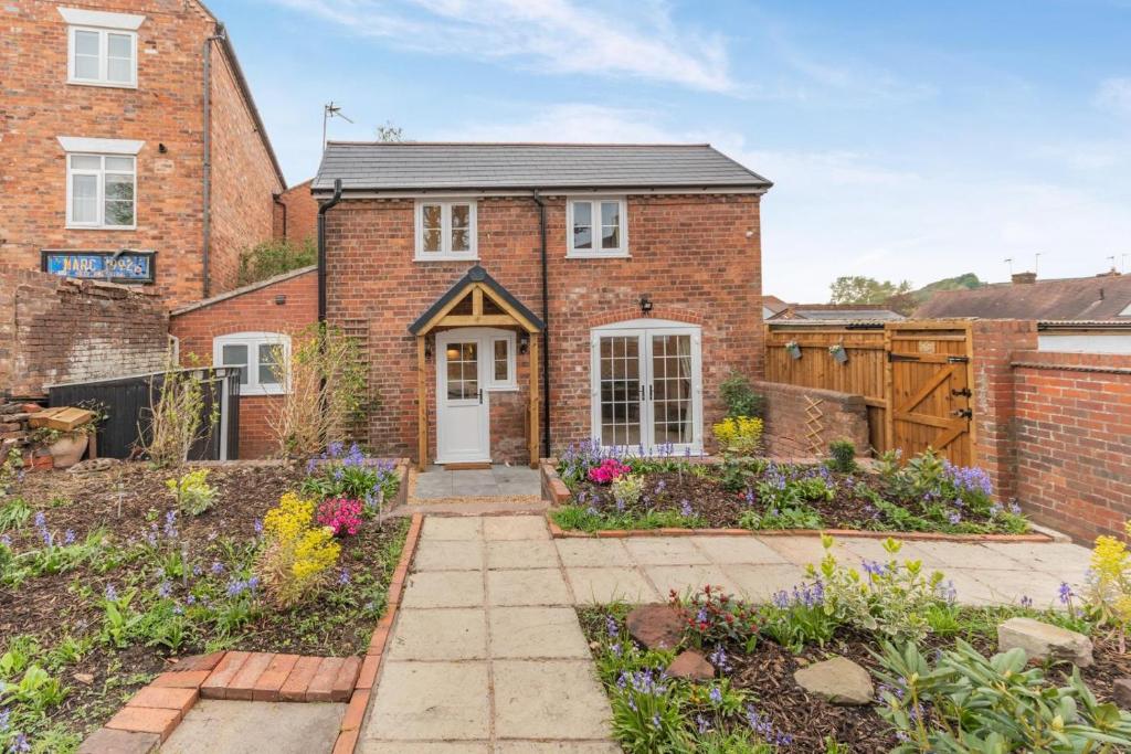 une maison en briques avec un jardin devant dans l'établissement No Road - The Cottage, à Bewdley