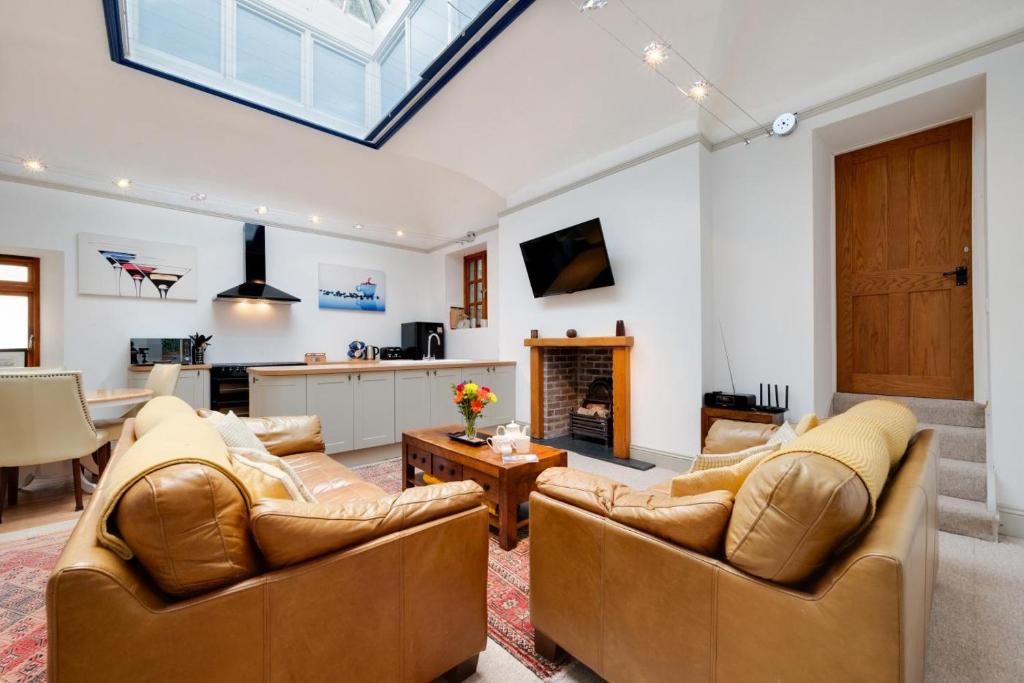 ein Wohnzimmer mit 2 Sofas und einer Küche in der Unterkunft The Orangery Lynton Cottage in Lynmouth